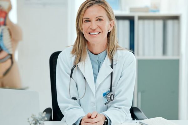 Ärztin sitzt in ihrer Praxis und lächelt