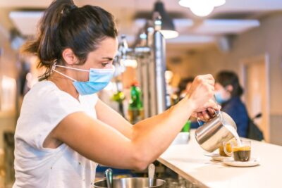 Mitarbeiterin bereitet Kaffee für Kunden zu